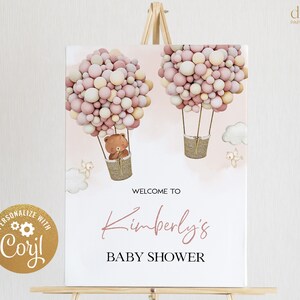 Puede incluir: Un cartel blanco con acentos rosados y marrones que presenta dos globos aerost&aacute;ticos llenos de globos rosados y crema. Los globos llevan un osito de peluche y un p&aacute;jaro. El cartel dice "Bienvenido al Baby Shower de Kimberly".