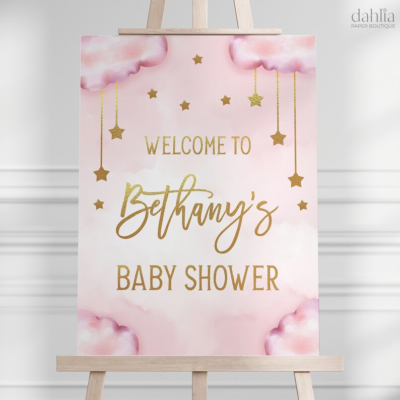 Może przedstawiać: R&oacute;żowo-złoty napis powitalny na baby shower z chmurami i gwiazdami. Napis brzmi "Witamy na baby shower Bethany".