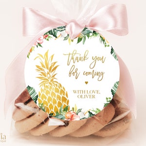 May include: A round, white favor tag with a gold pineapple design and the text "Thank you for coming" in gold script. The tag is surrounded by a green and pink floral border. The text "With love, Oliver" is printed in gold at the bottom of the tag.