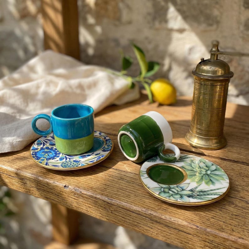 Puede incluir: Un juego de tres tazas de cer&aacute;mica con un acabado mate moteado. Las tazas son en tonos crema, gris claro y gris oscuro. Cada taza tiene un dise&ntilde;o simple y minimalista y un asa redondeada.