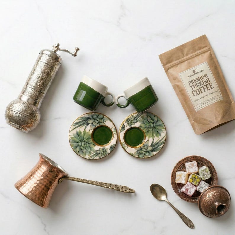May include: An assortment of Turkish coffee items, including two green and white coffee cups, matching saucers with a succulent design, a copper coffee pot, a coffee grinder, a bag of coffee, and a small dish of Turkish delight.