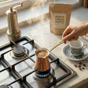 Brewing authentic Turkish coffee on a real stovetop using a small handcrafted hammered copper cezve and a vintage silver stirring spoon.