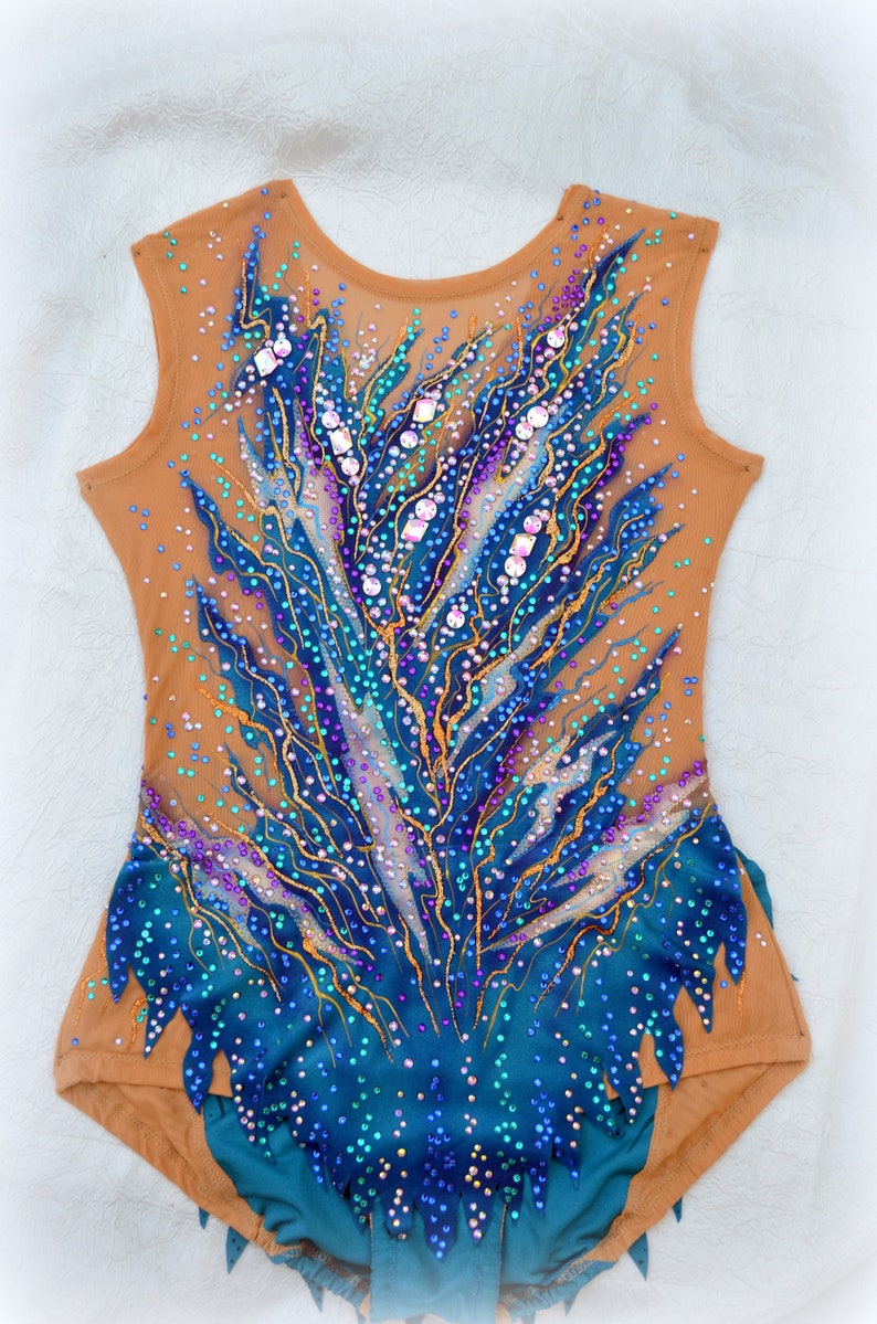 May include: A teal and brown leotard with a blue and gold design. The leotard is covered in rhinestones and sequins.