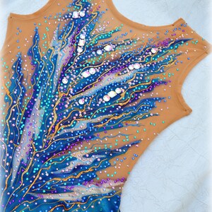 May include: A brown leotard with a blue, teal, and gold design. The leotard is covered in rhinestones and sequins.