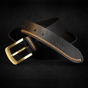 May include: Black leather belt with a gold-colored buckle. The belt features decorative stitching in a lighter brown color along the edges. The brand name "TORROSS" is embossed on the belt.