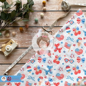 May include: White fabric with a red, white, and blue patriotic print featuring cherries, fireworks, stars, bows, and ice cream cones. The fabric is folded in half and a measuring tape is visible in the background.