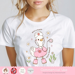 Puede incluir: Una camiseta blanca con un ganso de dibujos animados rosa que lleva un gorro de enfermera y sostiene un estetoscopio. El ganso est&aacute; rodeado de flores y el texto "Registered Silly Goose".