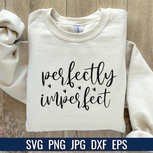 K&ouml;nnte beinhalten: Cremefarbenes Sweatshirt mit dem Schriftzug "perfectly imperfect" in schwarzer Schrift, akzentuiert mit kleinen Herzformen. Am unteren Bildrand steht der Text "SVG PNG JPG DXF EPS".