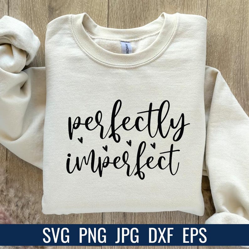 K&ouml;nnte beinhalten: Cremefarbenes Sweatshirt mit dem Schriftzug "perfectly imperfect" in schwarzer Schrift, akzentuiert mit kleinen Herzformen. Am unteren Bildrand steht der Text "SVG PNG JPG DXF EPS".