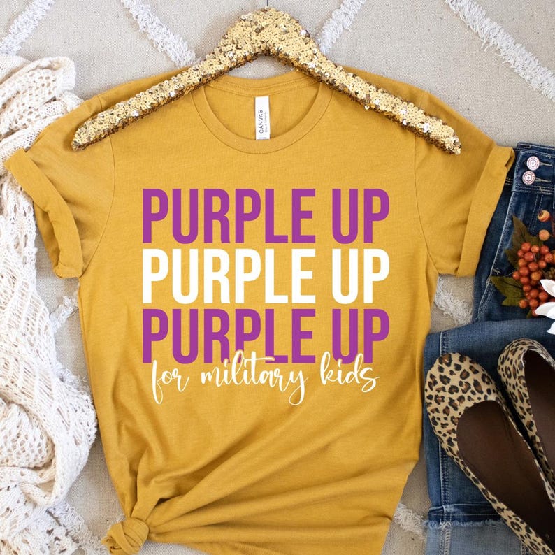 May include: A mustard yellow t-shirt with the text "Purple Up Purple Up Purple Up for military kids" in white and purple lettering.