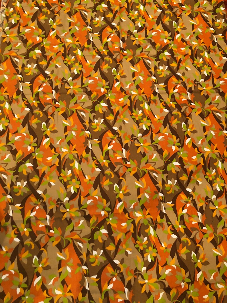 Op de afbeelding: Een stof met een herhalend patroon van gestileerde bloemen in tinten bruin, oranje, groen en wit.