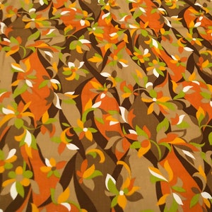 Op de afbeelding: Een stof met een herhalend patroon van gestileerde bloemen in tinten bruin, oranje, wit en groen.