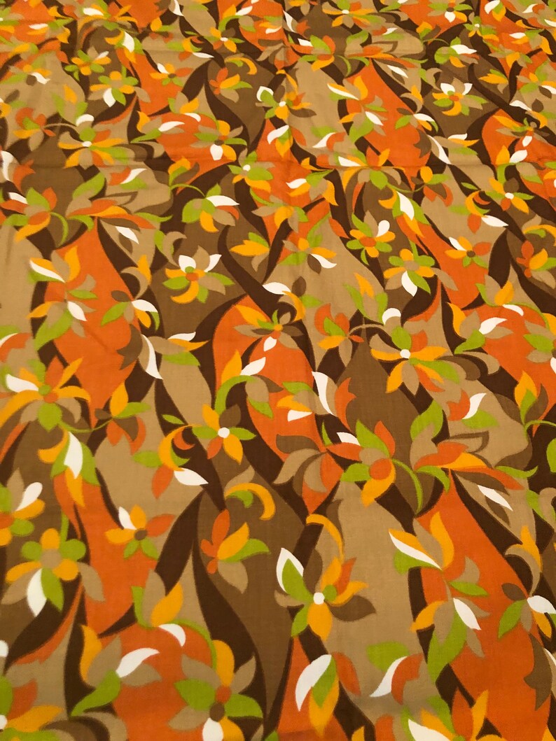 Op de afbeelding: Een stof met een herhalend patroon van gestileerde bloemen in tinten bruin, oranje, wit en groen.