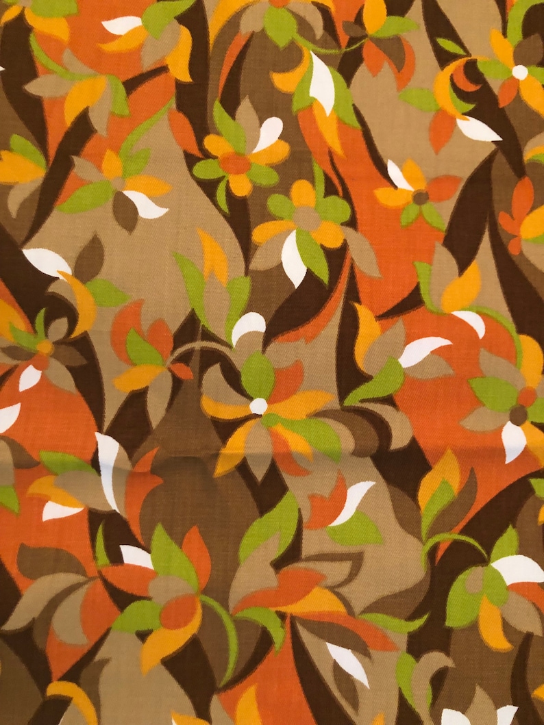 Op de afbeelding: Een stof met een herhalend patroon van gestileerde bloemen in tinten bruin, oranje, geel, groen en wit.