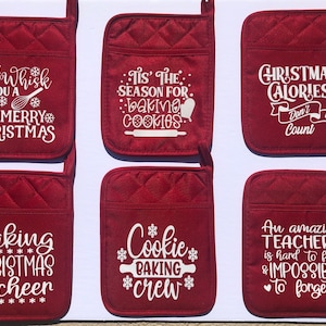 May include: Six burgundy oven mitts with white text. The mitts have various holiday-themed phrases, including "We Whisk You a Merry Christmas" and "Christmas Calories Don't Count." Each mitt has a quilted pattern.