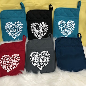 May include: Set of six quilted oven mitts with heart-shaped designs and various text, including "Nana", "Best Auntie Ever", "Happy Mother's Day", "Grandma", "Abuela", and a blank mitt.