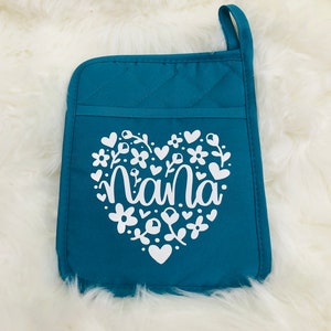 May include: Teal quilted oven mitt with a white heart design featuring the word "nana" surrounded by flowers and hearts.