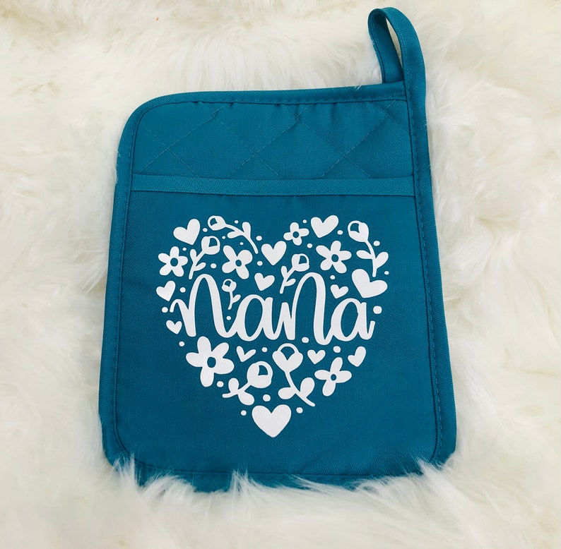May include: Teal quilted oven mitt with a white heart design featuring the word "nana" surrounded by flowers and hearts.