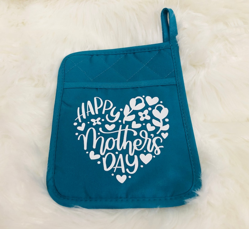 May include: Teal blue quilted oven mitt with a white heart design that says "Happy Mother's Day" with floral accents.