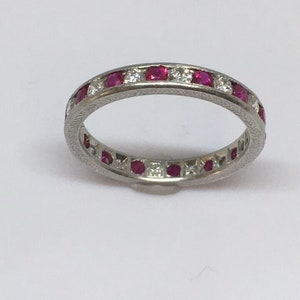 May include: A platinum eternity band with a row of round rubies and diamonds.