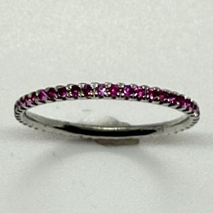 May include: A thin silver band ring with a row of small pink gemstones.