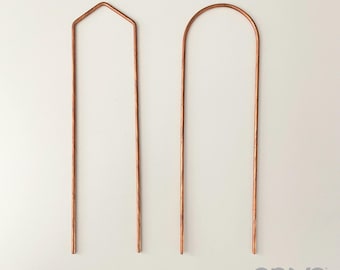 May include: Two copper garden plant supports. One has a pointed top, the other a rounded top. The supports are made of copper tubing and are designed to help plants grow upright. The supports are on a white background.
