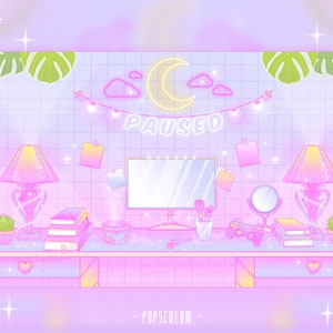 May include: A pastel pink and blue themed desk with a computer monitor, two lamps, books, a cup of tea, and a game controller. The desk is decorated with a neon sign that says "PAUSED" and a string of lights.