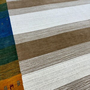 May include: A white and brown striped rug with a colorful border. The border features stripes of orange, yellow, green, blue, and red.