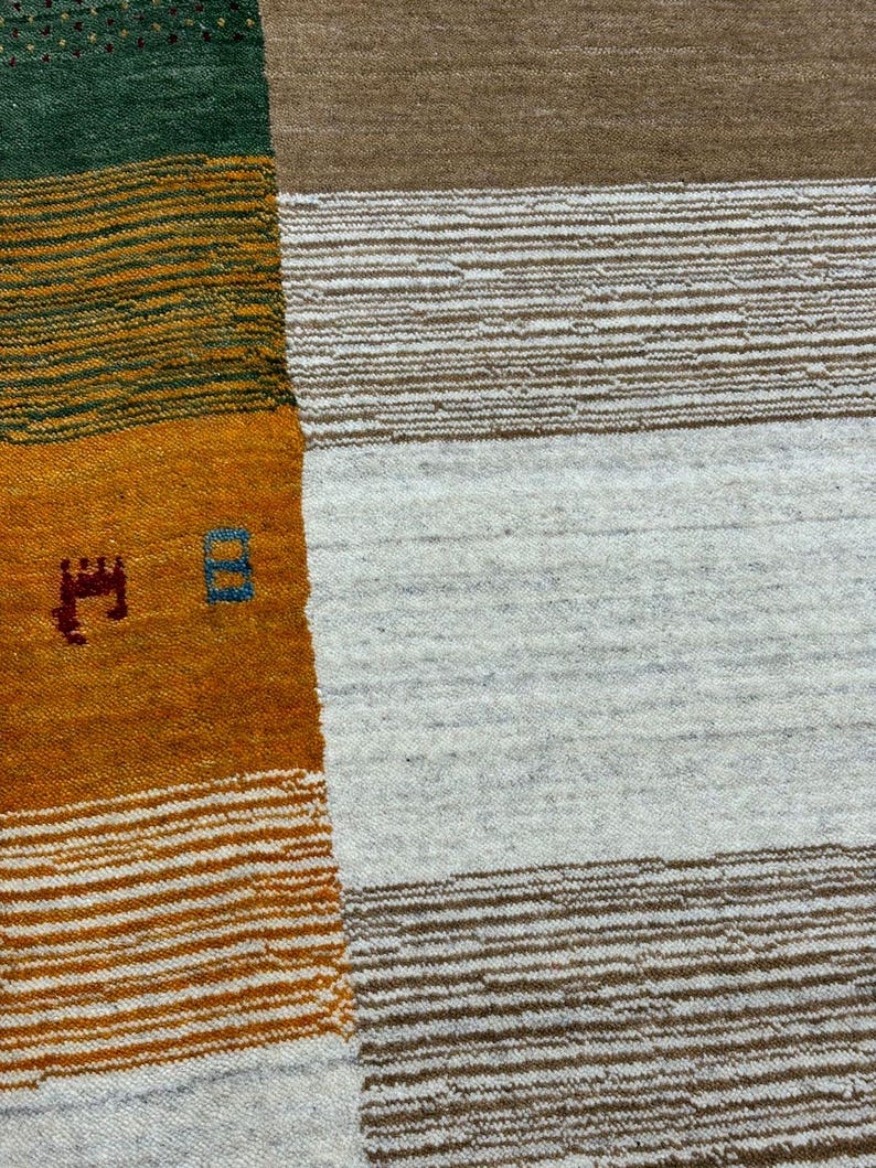 May include: A close-up of a woven rug with a geometric pattern. The rug is made of different colored yarns, including green, yellow, orange, and white. The rug has a textured surface.