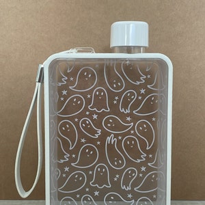 May include: A clear, rectangular water bottle with a white cap and frame. The bottle features a repeating pattern of white ghost and star illustrations. A white strap is attached to the side for carrying.