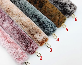 May include: Six different colors of faux fur straps with gold metal clasps. The straps are numbered 1 through 6.