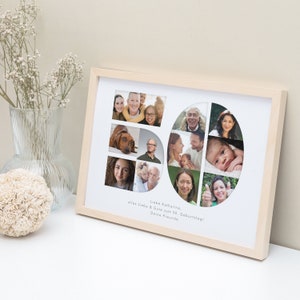 May include: A framed photo collage in a light wood frame with a white mount. The collage is made up of photos of different people and a dog. The photos are arranged in the shape of the number 50. The text "Liebe Katharina, alles Liebe & Gute zum 50. Geburtstag! Deine Freunde" is printed below the collage.