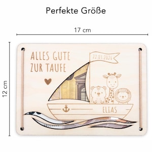 K&ouml;nnte beinhalten: Holzsparein in Form eines Bootes mit einem Schlitz f&uuml;r Geldscheine. Die Box ist mit einem Herz, einem Anker und dem Text "Alles Gute zur Taufe" und "Elias" verziert. Die Box ist 12 cm hoch und 17 cm breit.