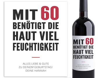 May include: A white card with black text that reads "MIT 60 BENÖTIGT DIE HAUT VIEL FEUCHTIGKEIT" and "ALLES LIEBE & GUTE ZU DEINEM GEBURTSTAG! DEINE HANNAH". A red wine bottle with a white label that reads "MIT 60 BENÖTIGT DIE HAUT VIEL FEUCHTIGKEIT" and "ALLES LIEBE & GUTE ZU DEINEM GEBURTSTAGI DEINE HANNAH".