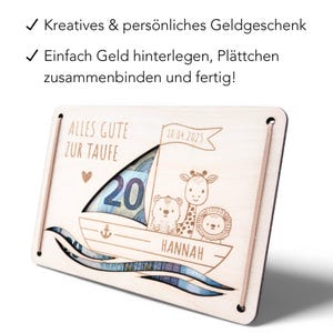 K&ouml;nnte beinhalten: Eine h&ouml;lzerne Geldbox in Form eines Segelboots mit einem Schlitz f&uuml;r Geldscheine. Die Box ist mit einer Giraffe, einem L&ouml;wen und einem B&auml;ren verziert. Der Text "ALLES GUTE ZUR TAUFE" und "HANNAH" sind in die Box graviert. Das Datum "10.04.2025" ist ebenfalls in die Box graviert.