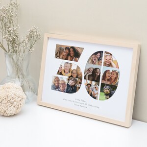 May include: A white photo frame with a light wood frame. The frame contains a collage of photos arranged in the shape of the number 30. The text "Liebe Tabea, alles Liebe & Gute zum 30. Geburtstag, Deine Familie" is printed below the collage.