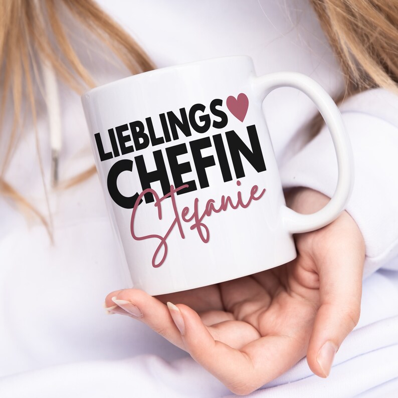 May include: White ceramic mug with black text that reads "Lieblings Chefin Stefanie" with a pink heart.