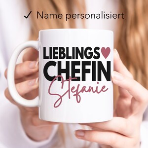 May include: White ceramic mug with a black and pink design. The mug says "Lieblings Chefin" with a pink heart and the name "Stefanie" in pink script.