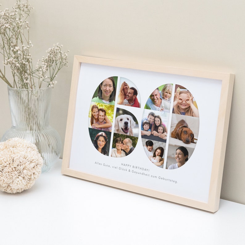 Op de afbeelding: Een wit fotolijstje met een houten lijst in houtkleur. Het lijstje bevat een collage van foto's in de vorm van het getal 60. De foto's zijn van een familie en een hond. De tekst "Happy Birthday! Alles Gute, viel Gl&uuml;ck & Gesundheit zum Geburtstag" staat onder de collage.