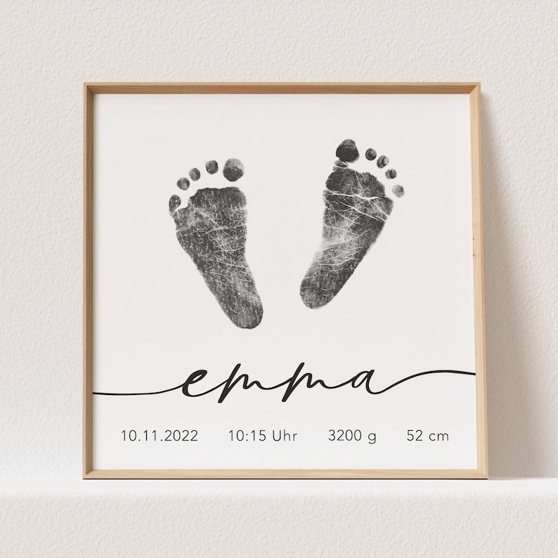 May include: Black and white footprint art print with the name "emma" written in cursive. The print also includes the date "10.11.2022", time "10:15 Uhr", weight "3200 g", and length "52 cm".