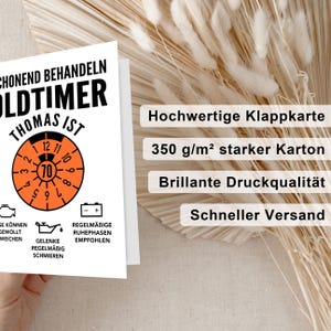 May include: A white card with black and orange text and a black and orange speedometer graphic. The text reads "CHONEND BEHANDELN OLDTIMER THOMAS IST". The speedometer graphic has a black needle pointing to the number 70. The card also has a black and orange illustration of a car engine and a black and orange battery. The text below the speedometer graphic reads "REGELM&Auml;BIGE RUHEPHASEN EMPFOHLEN" and "GELENKE REGELM&Auml;BIG SCHMIEREN". The card is on a background of beige and white.