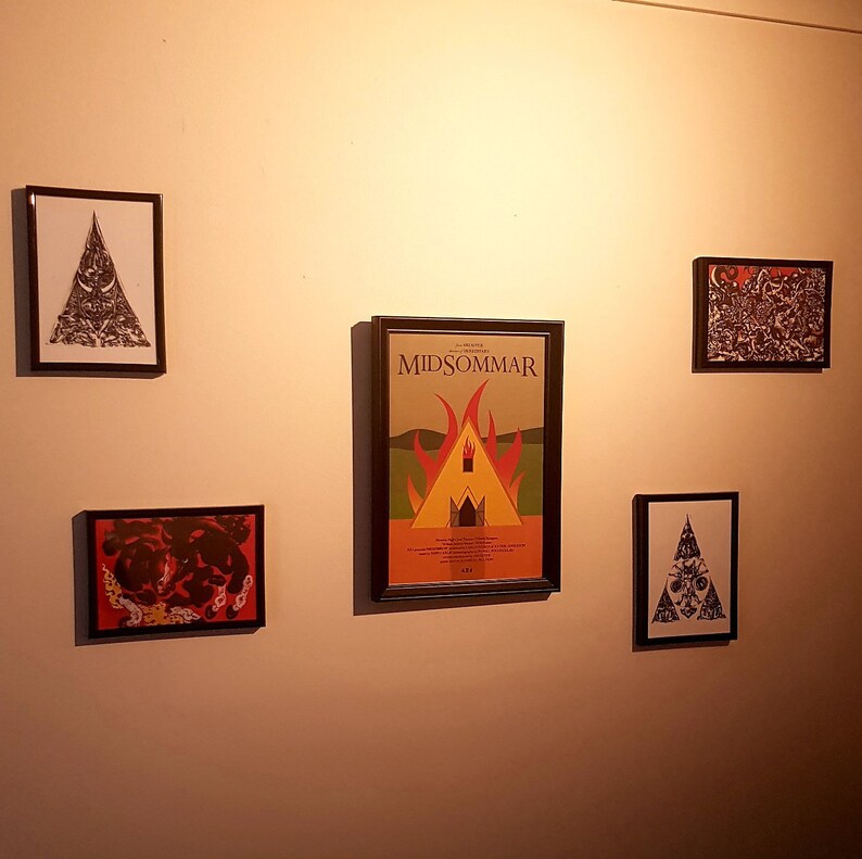 May include: A wall gallery with four framed prints. The center print is a movie poster for the film "Midsommar" with a red, orange, and yellow image of a burning building. The other three prints are black and white with abstract designs.