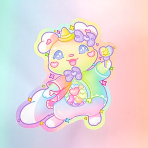 以下が含まれることがあります： 黄色い帽子と紫のリボン、虹の杖を持ったパステルレインボーカラーの漫画の動物。動物はハート柄の緑とピンクの服を着ています。背景はピンク、イエロー、ブルーのグラデーションです。