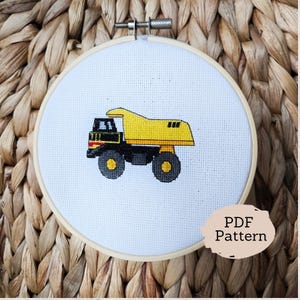 May include: A yellow and black dumper truck cross stitch pattern in a wooden embroidery hoop. The pattern is labelled "PDF Pattern".