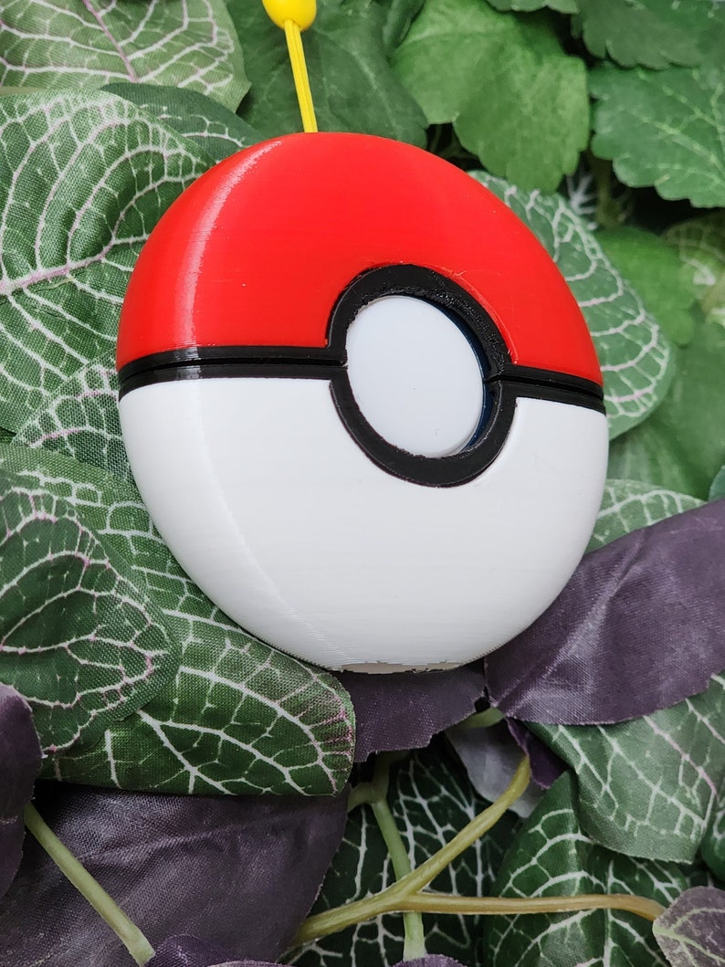 May include: A white and red Pokeball with a black ring around the center. The Pokeball is 3D printed.