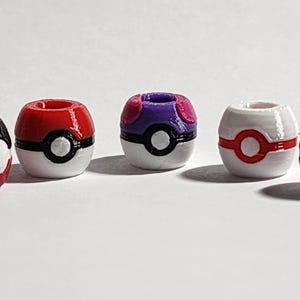 Peut inclure: Cinq perles sph&eacute;riques con&ccedil;ues pour ressembler &agrave; divers r&eacute;cipients en forme de boule. Les perles pr&eacute;sentent des combinaisons de couleurs distinctes, notamment rouge et noir, violet et blanc, et blanc avec des accents rouges, chacune avec un d&eacute;tail circulaire central.
