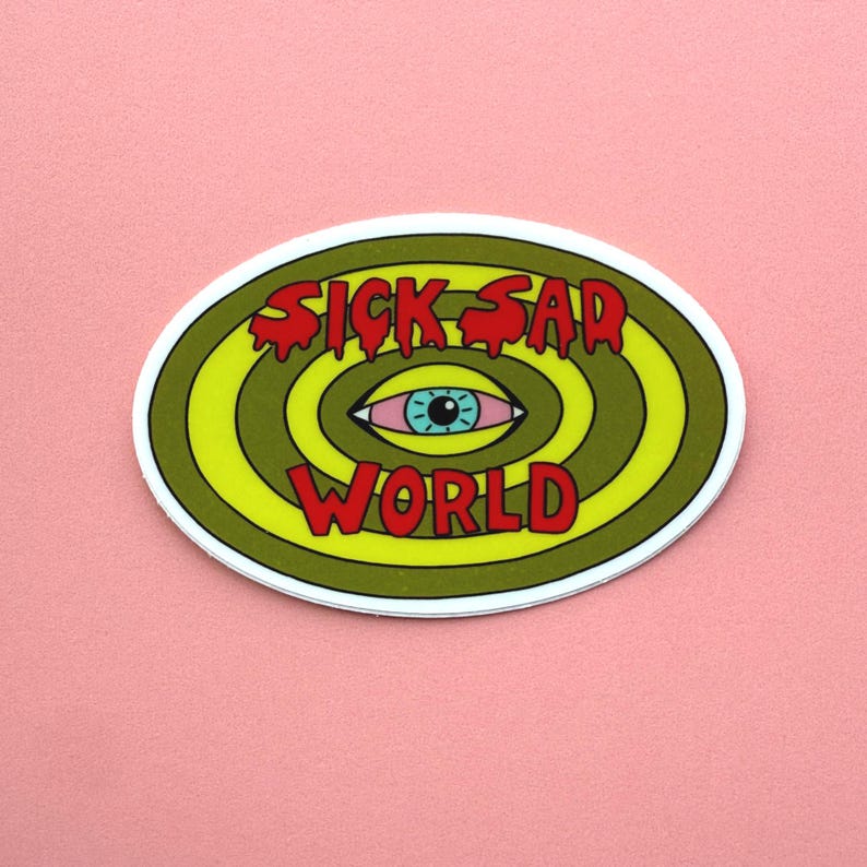 K&ouml;nnte beinhalten: Ovaler Aufkleber mit den Worten "SICK SAD WORLD" in roten, tropfenden Buchstaben. Das Design zeigt ein blau&auml;ugiges Auge in der Mitte, umgeben von konzentrischen gr&uuml;nen und gelben Kreisen, vor einem rosa Hintergrund.