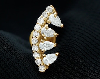 May include: A gold ear stud featuring a curved design adorned with a row of small round white stones and four larger pear-shaped white stones extending from the side. The piece includes the text WIIZLORY GEMS in the upper right corner.