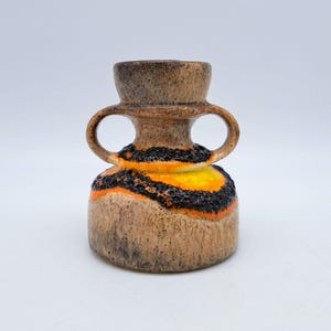 May include: A small, brown ceramic vase with two handles. The vase has a yellow and orange glaze with black accents.