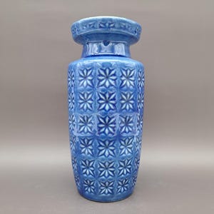 Könnte beinhalten: Eine blaue Keramikvase mit einem geometrischen Muster aus Sternen. Die Vase hat eine breite Öffnung und einen schmalen Boden.